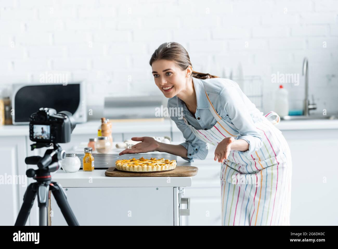 buon blogger culinario che punta con le mani a torta deliziosa vicino sfocato fotocamera digitale Foto Stock