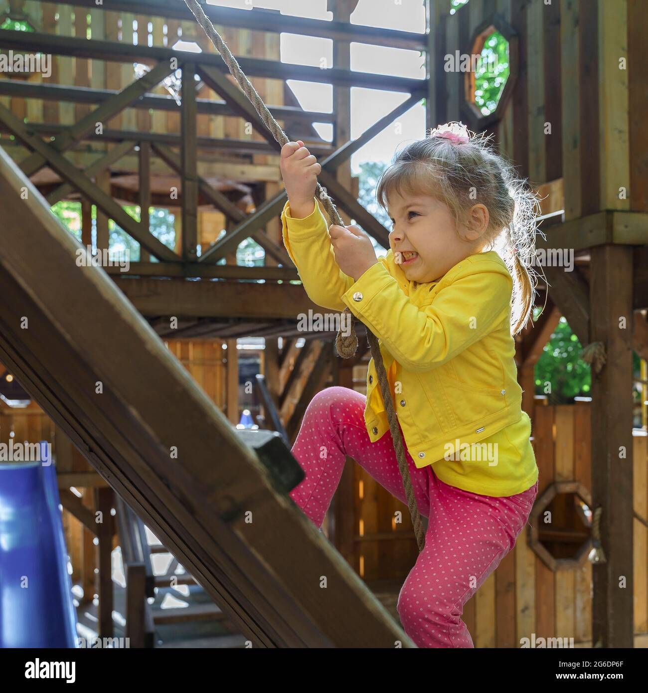 bambina in giacca gialla e pantaloni rosa sul parco giochi. Bambini  arrampicata corda all'aperto Bambini sano attività estiva crescita sana  Foto stock - Alamy