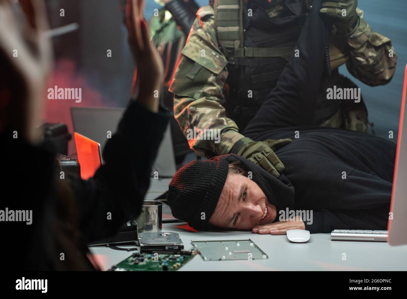 Rete criminale in felpa con cappuccio e cappuccio che viene presa da uomini in camouflage vestito Foto Stock