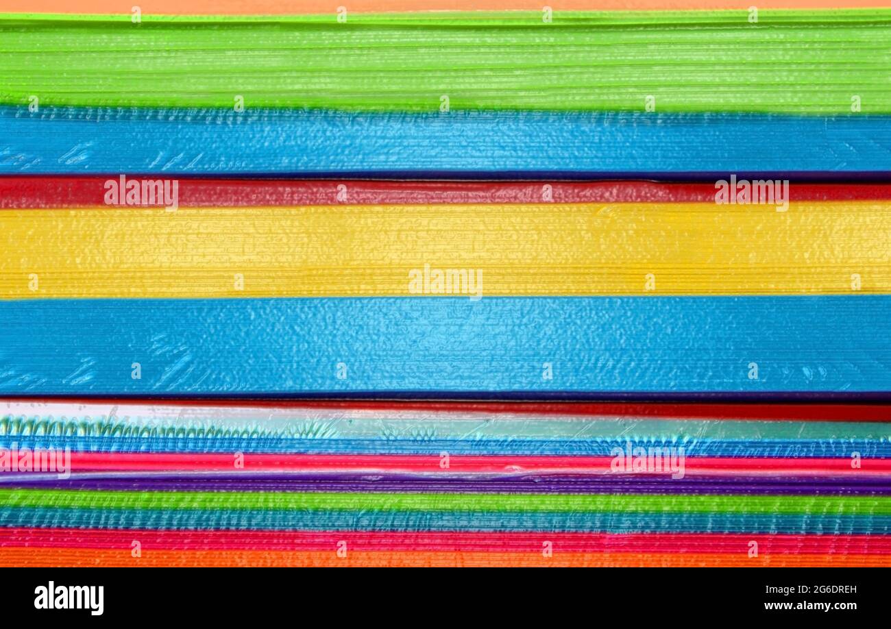 Le pile di carta in colori caldi e tonalità brillanti sono rivestite in plastica e si trovano in risme pronte per l'uso in ufficio. Foto Stock