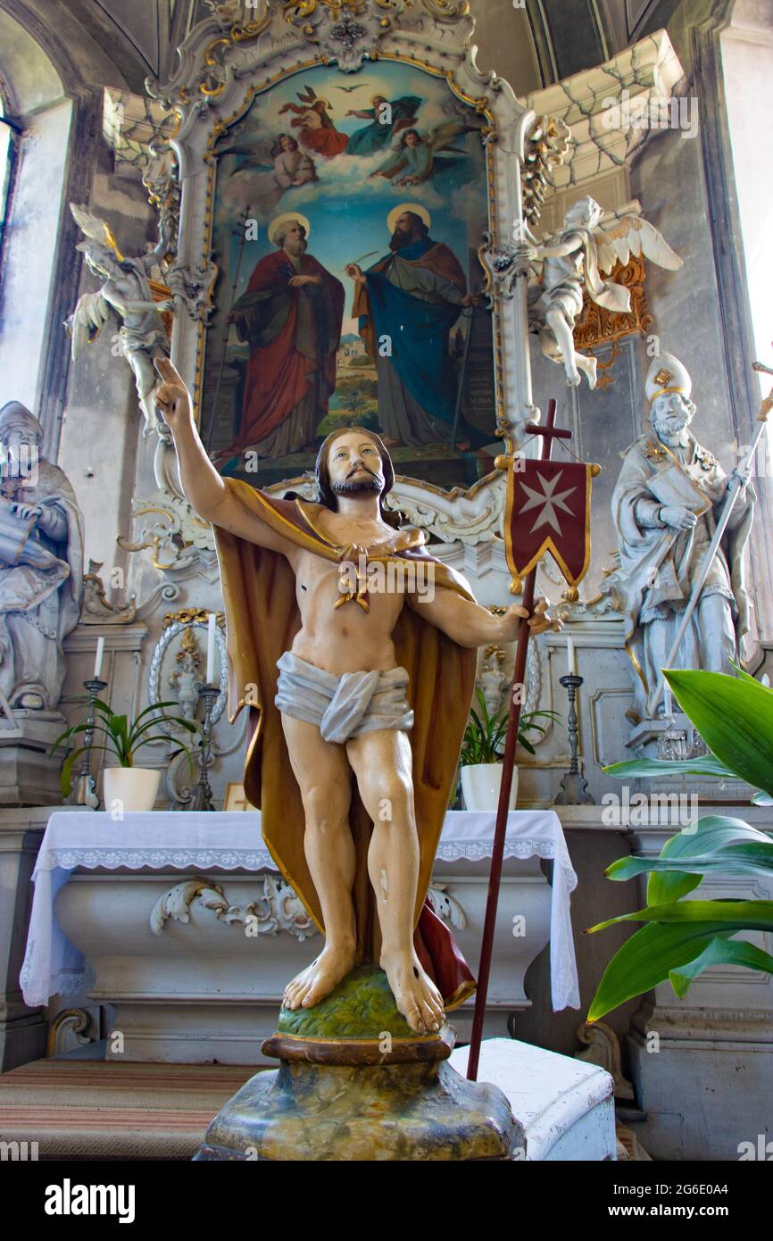 Statua di Gesù risurrezione con la bandiera a croce maltese all'interno della chiesa di fronte all'altare con dipinto di San Pietro e Paolo. Foto Stock