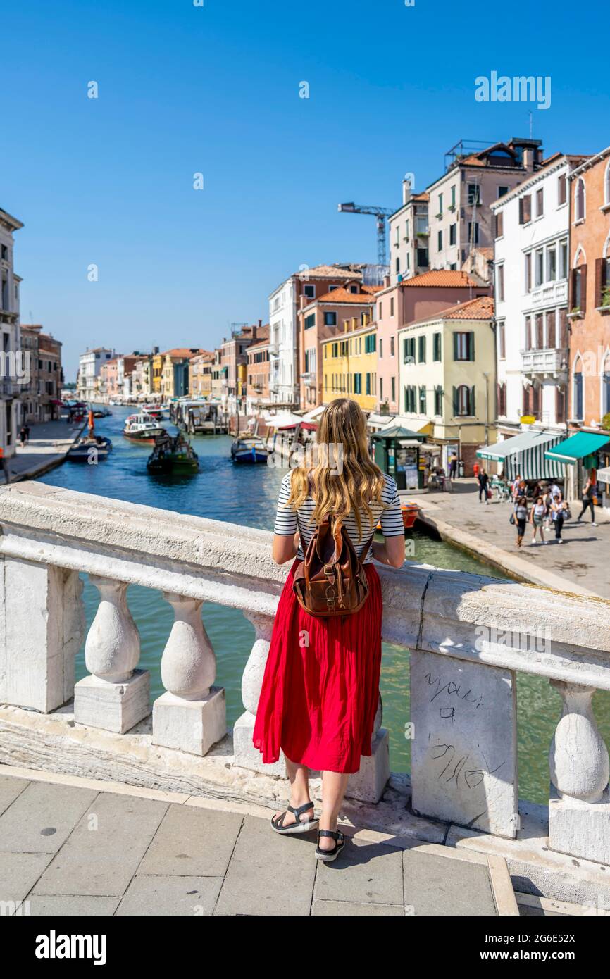 Giovane donna in abito rosso che guarda al Canal Grande, Ponte Scalzi, Venezia, Veneto, Italia Foto Stock