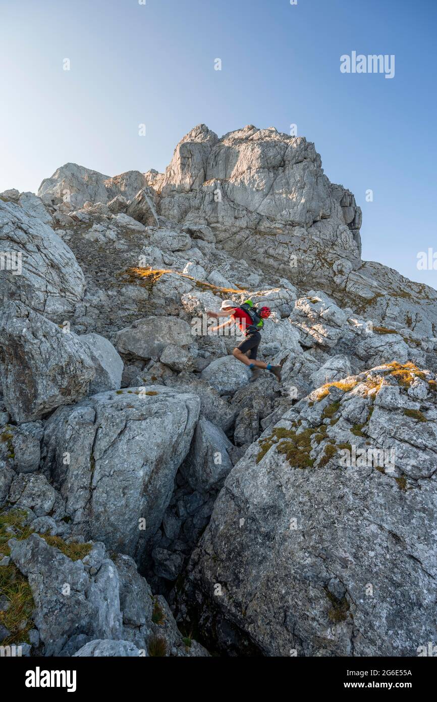 Uomo che salta da roccia a roccia, escursioni al Hochkalter, Berchtesgadener Alpen, Berchtesgadener Land, alta Baviera, Baviera, Germania Foto Stock