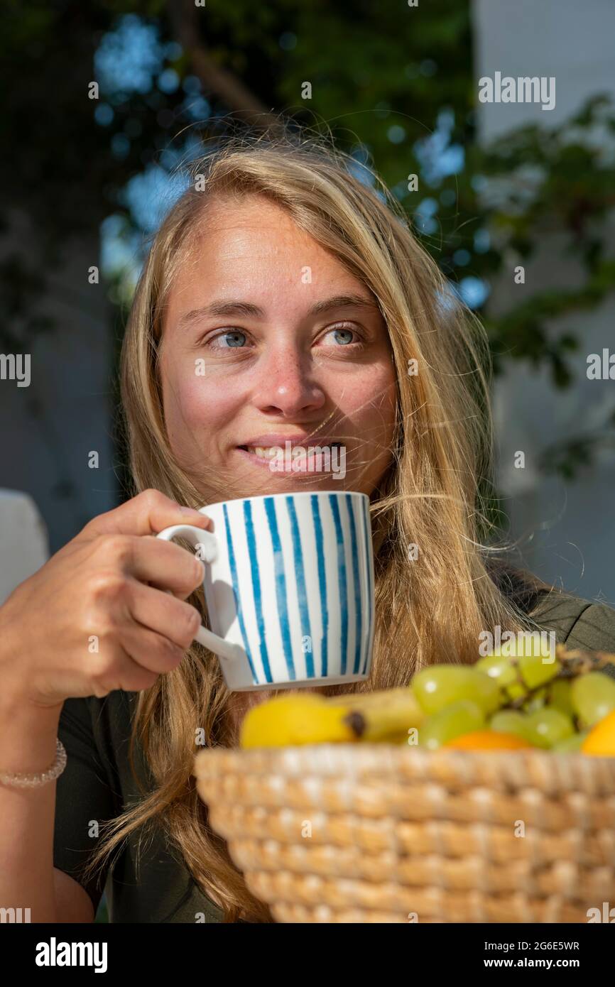 Giovane donna che tiene il bicchiere, colazione in vacanza fuori, Grecia Foto Stock