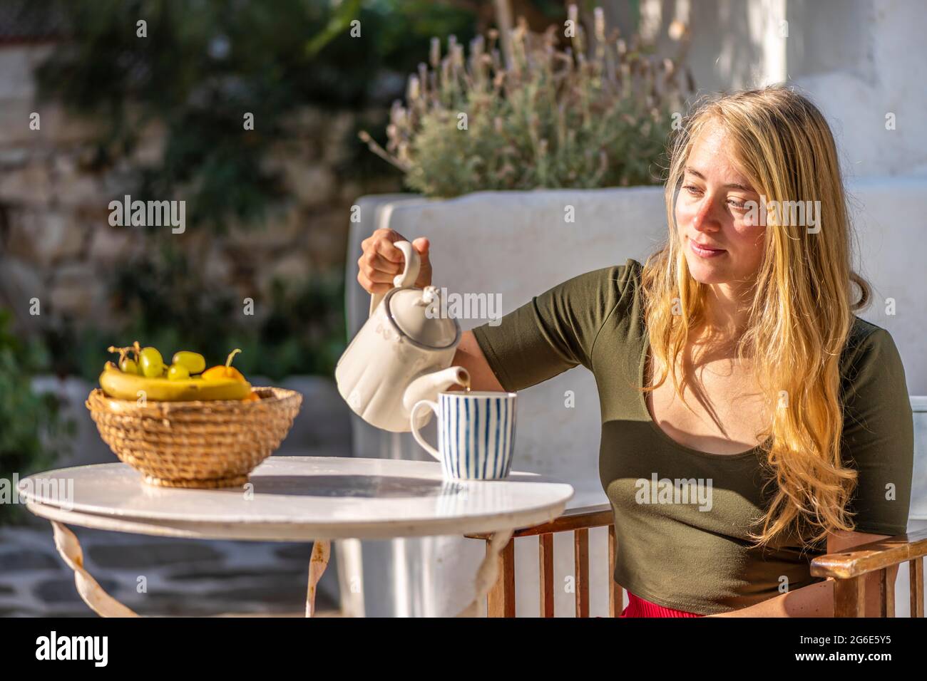 La giovane donna si versa il tè, la colazione in vacanza fuori, Grecia Foto Stock