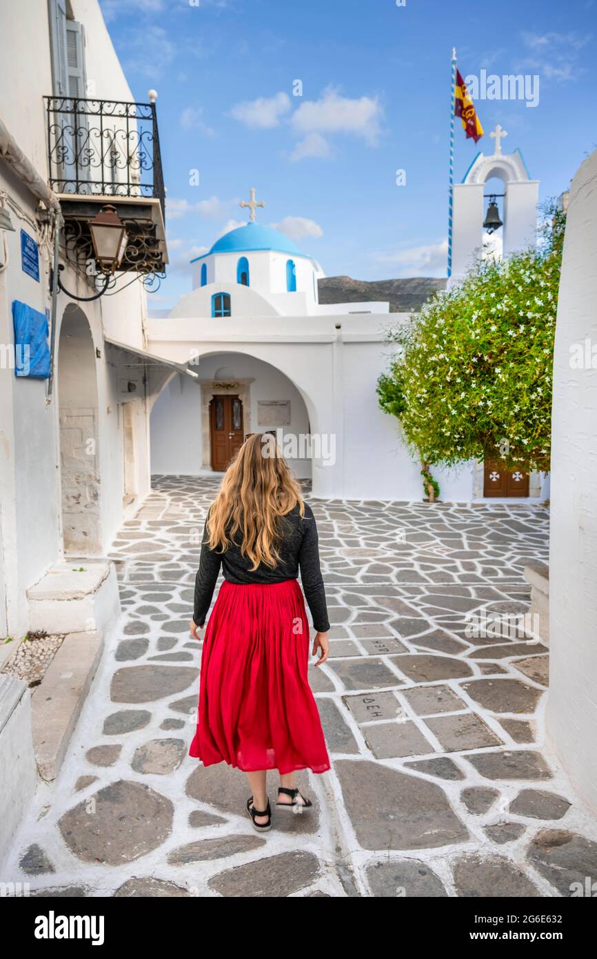 Tourist con abito rosso, blu e bianco greco ortodosso Chiesa Î Î±Î¼Î¼Î­Î³Î¹ÏƒÏ„Ï‰Î½ Î¤Î±Î¾Î¹Î±ÏÏ‡ÏŽÎ½ nel centro storico di Parikia, Paros, Cicladi Foto Stock