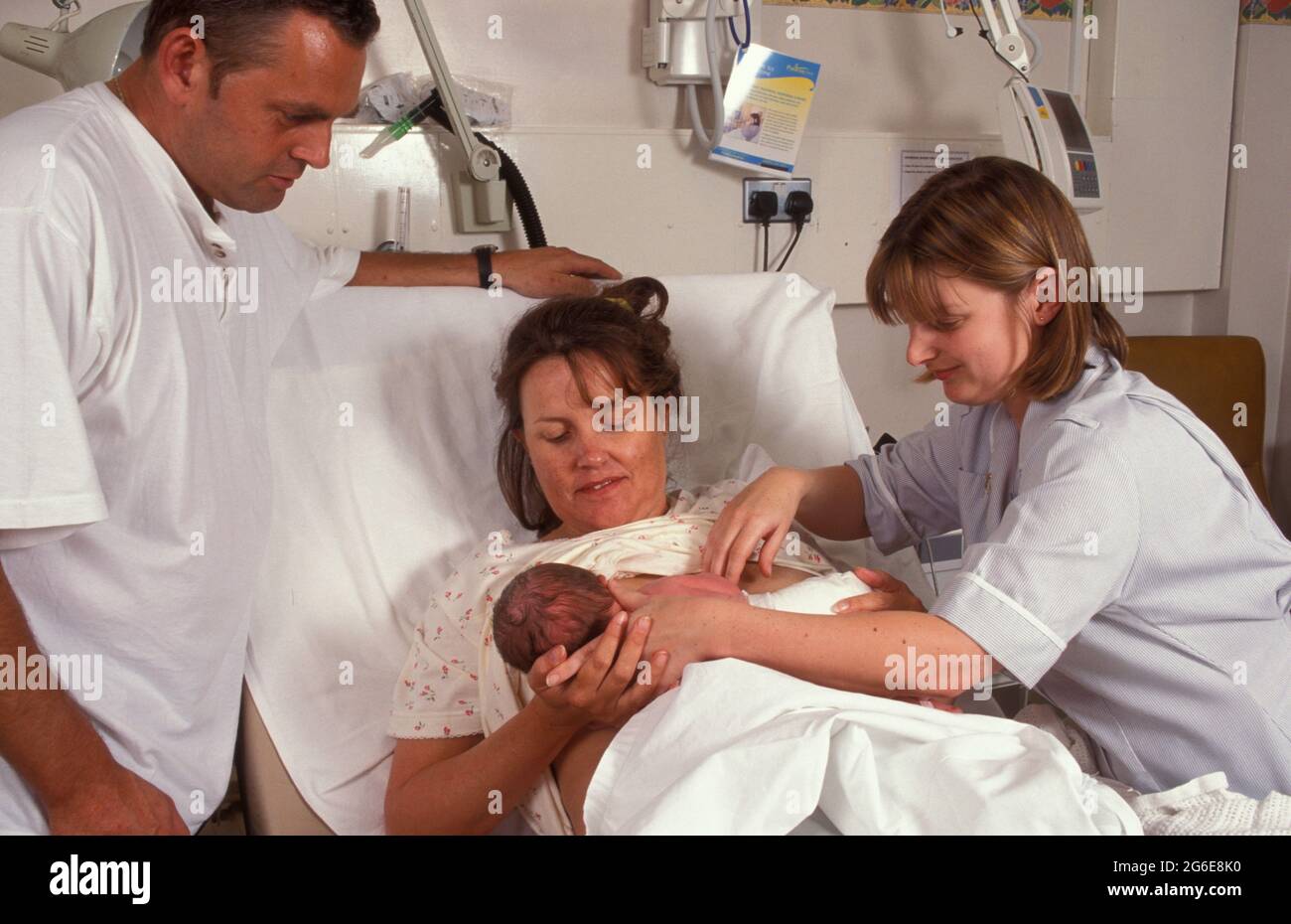 ostetrica studentesca che mostra ai nuovi genitori come allattare al seno Foto Stock