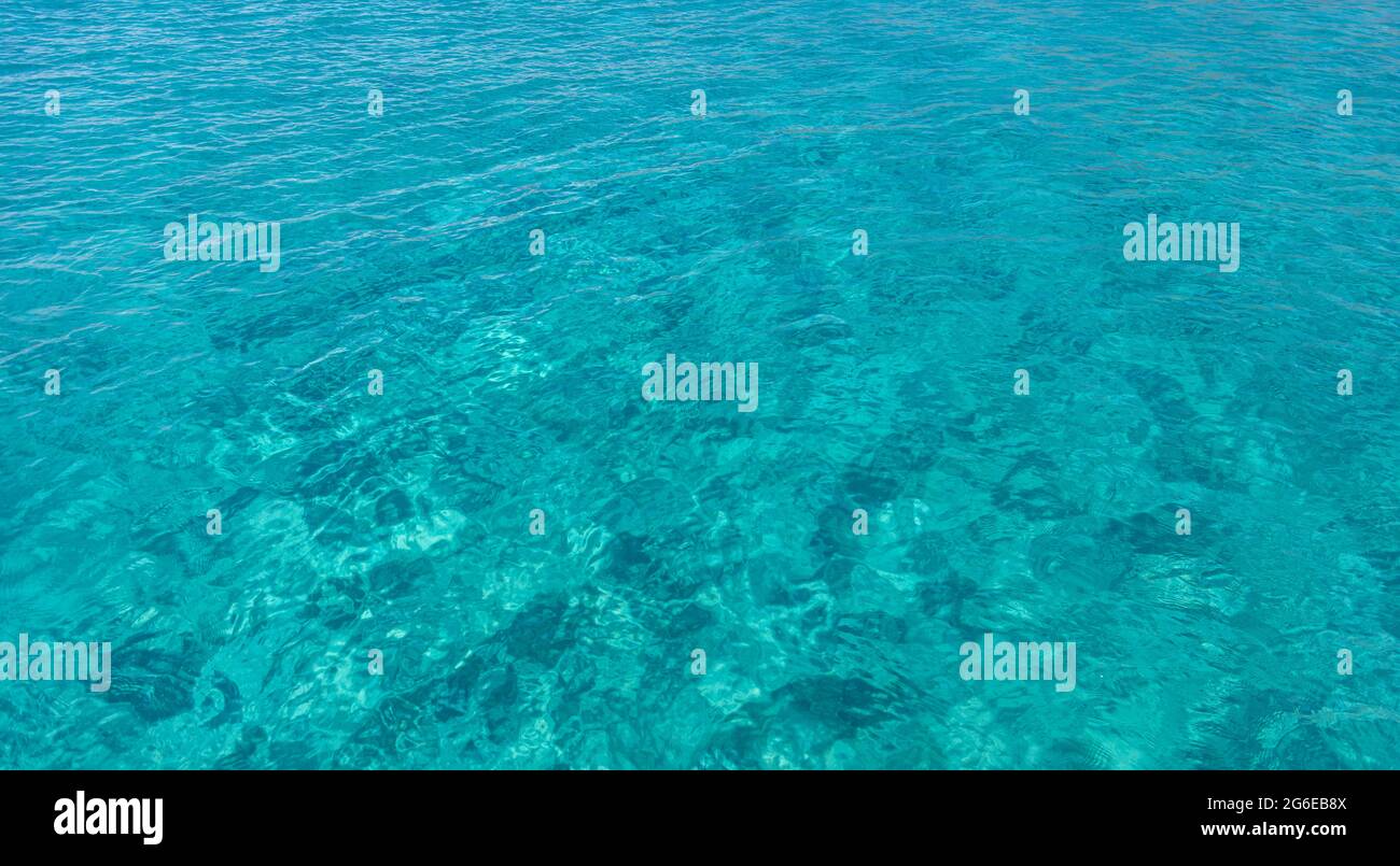 Fondo dell'acqua di mare, colore blu turchese, cristallo chiaro, alcuni riflessi. Superficie calma con piccole increspature, vacanze estive in un paradiso tropicale i Foto Stock