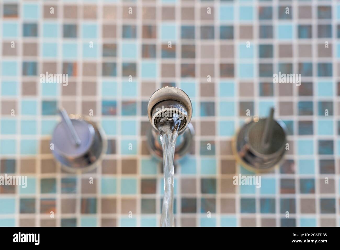 Primo piano su un rubinetto da bagno con acqua che scorre, Regno Unito. Concetto: Conservazione dell'acqua, spreco di acqua, risparmio di acqua, acqua domestica efficiente, uso di acqua, consumo Foto Stock