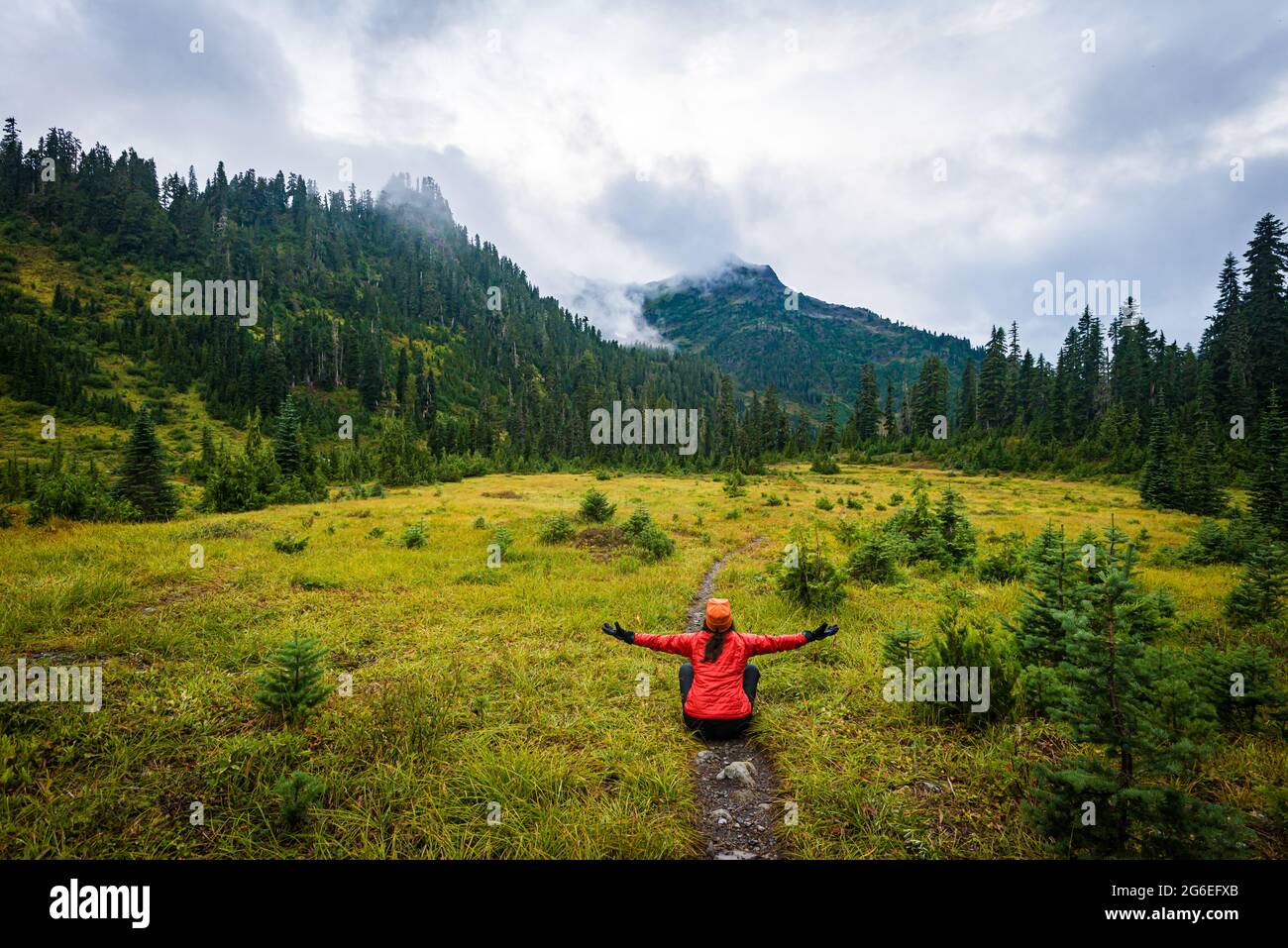 Escursionista nel Parco Nazionale Olimpico seduto sul sentiero che abbraccia le montagne Foto Stock