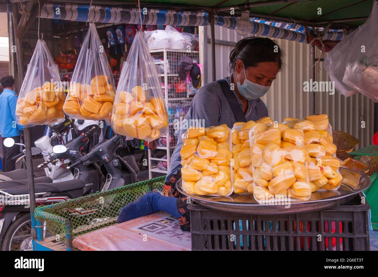 Una donna cambogiana, indossando una maschera protettiva viso / copertura, la preparazione confezionata di jackfruit fresco su un carrello mobile strada durante la pandemia COVID - 19. Steung Meanchey, Phnom Penh, Cambogia. 8 dicembre 2020. © Kraig Lieb Foto Stock