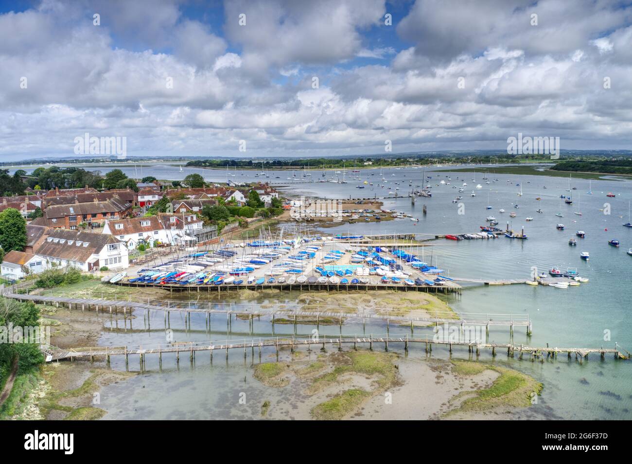 Itchenor nel Sussex occidentale con piccole barche accanto al molo con yacht e barche sull'estuario più una vista del cantiere. Foto aerea. Foto Stock