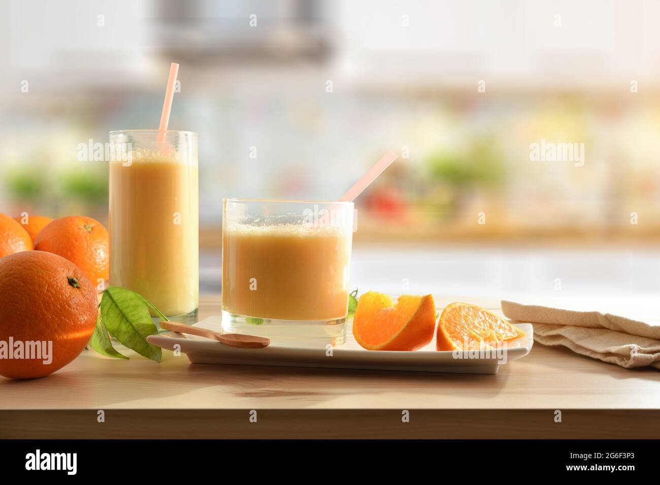 Bevanda di arancia naturale con latte e ciotola di frutta piena di arance su sfondo tavola di legno cucina. Vista frontale. Foto Stock