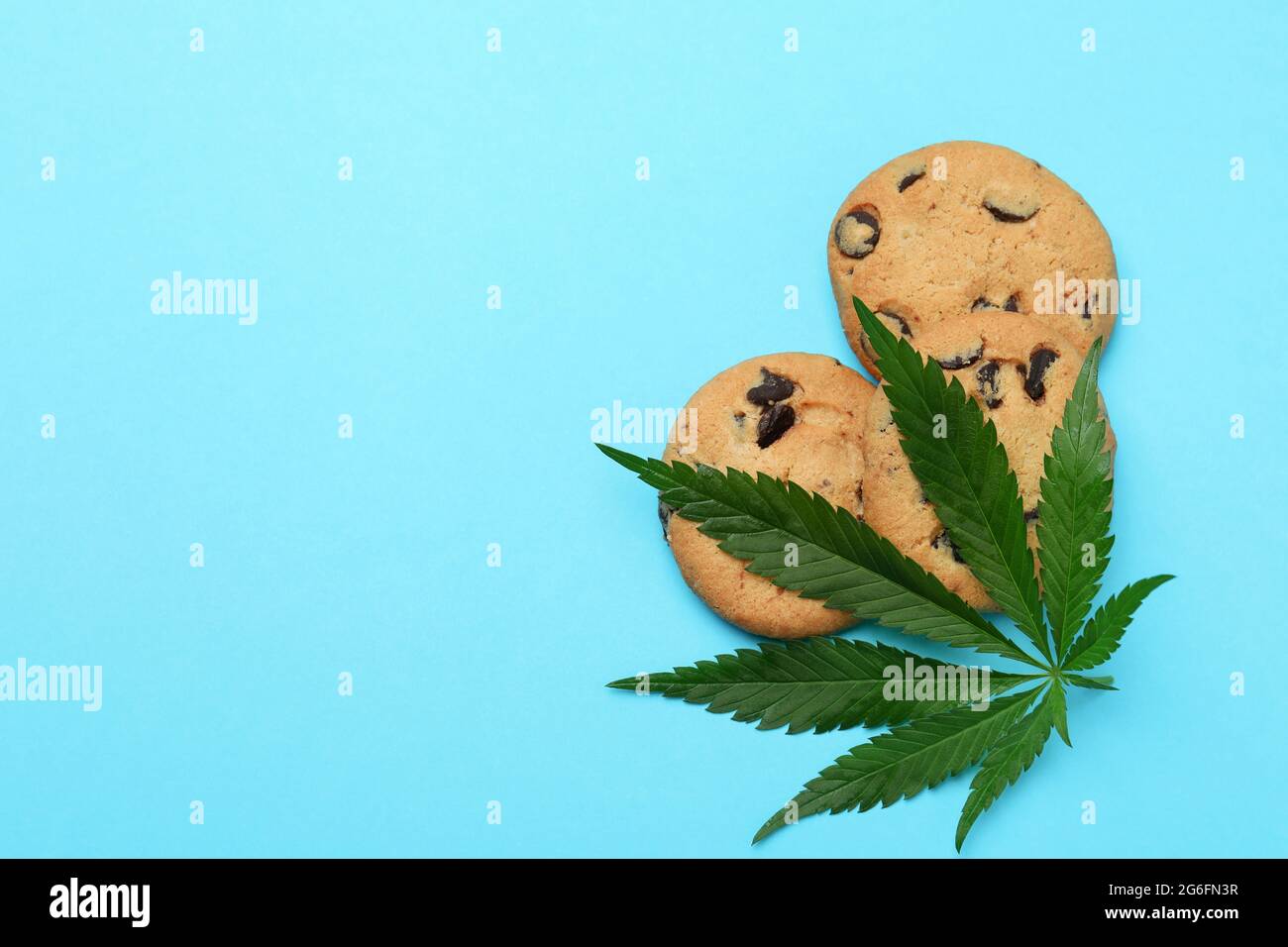 Biscotti e foglie di cannabis su sfondo blu Foto Stock