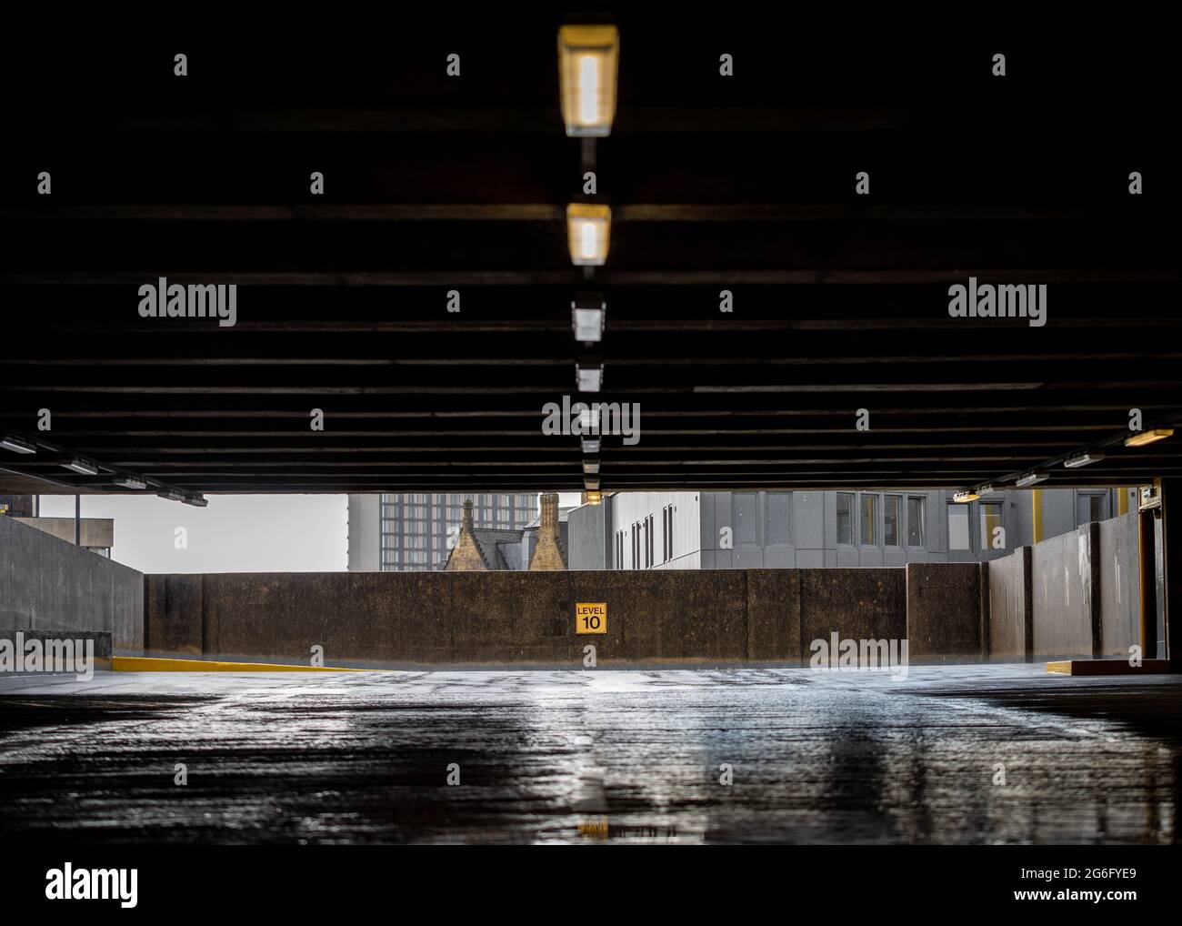 Parcheggio abbandonato a più piani con tetto crollato. Allagamento su pavimento in cemento, piscine d'acqua al livello dieci 10. Atmosfera oscura e inquietante. Foto Stock