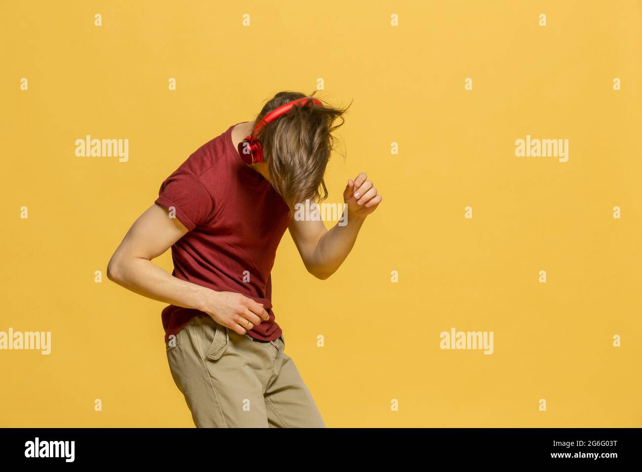 Studio ritratto giovane uomo con cuffie danzanti su sfondo giallo Foto Stock