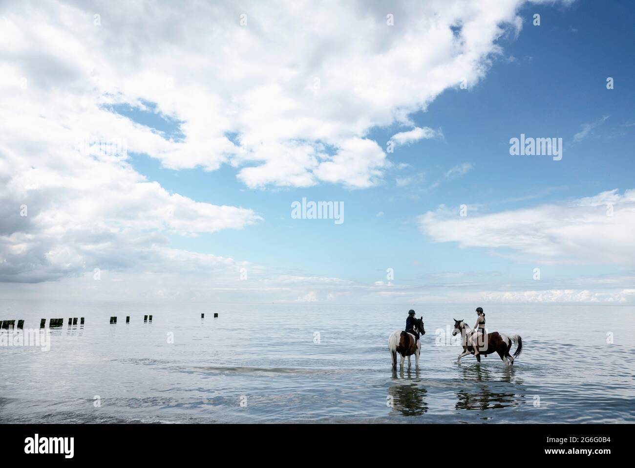 Ragazze che cavalcano cavalli nel Mar Baltico, Germania Foto Stock