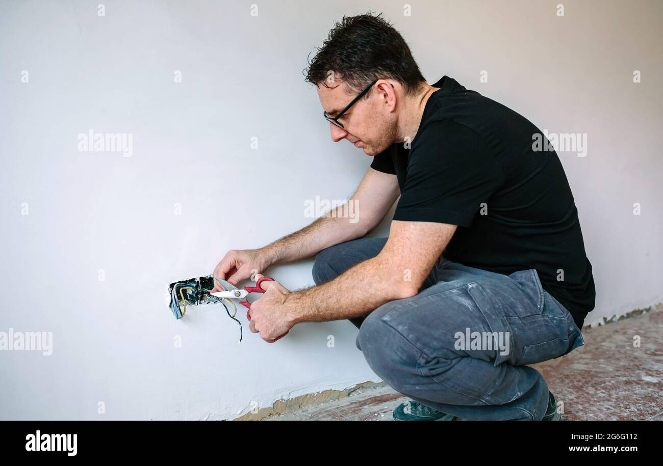 Elettricista che lavora sull'impianto elettrico di una casa Foto Stock