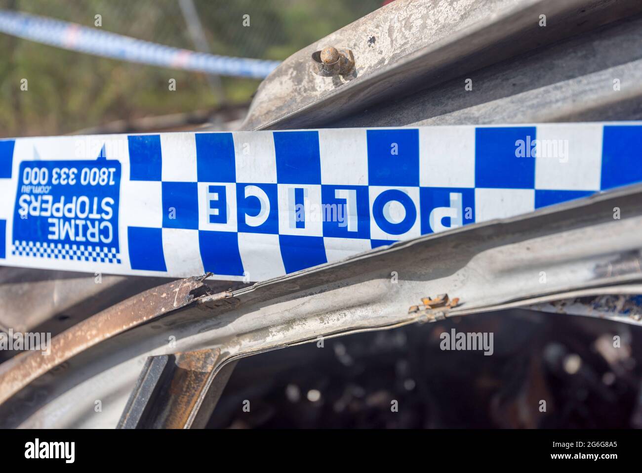 Nastro di polizia in una scena di crimine designata, avvolto intorno a un'automobile bruciata fuori a Sydney, nuovo Galles del Sud, Australia Foto Stock