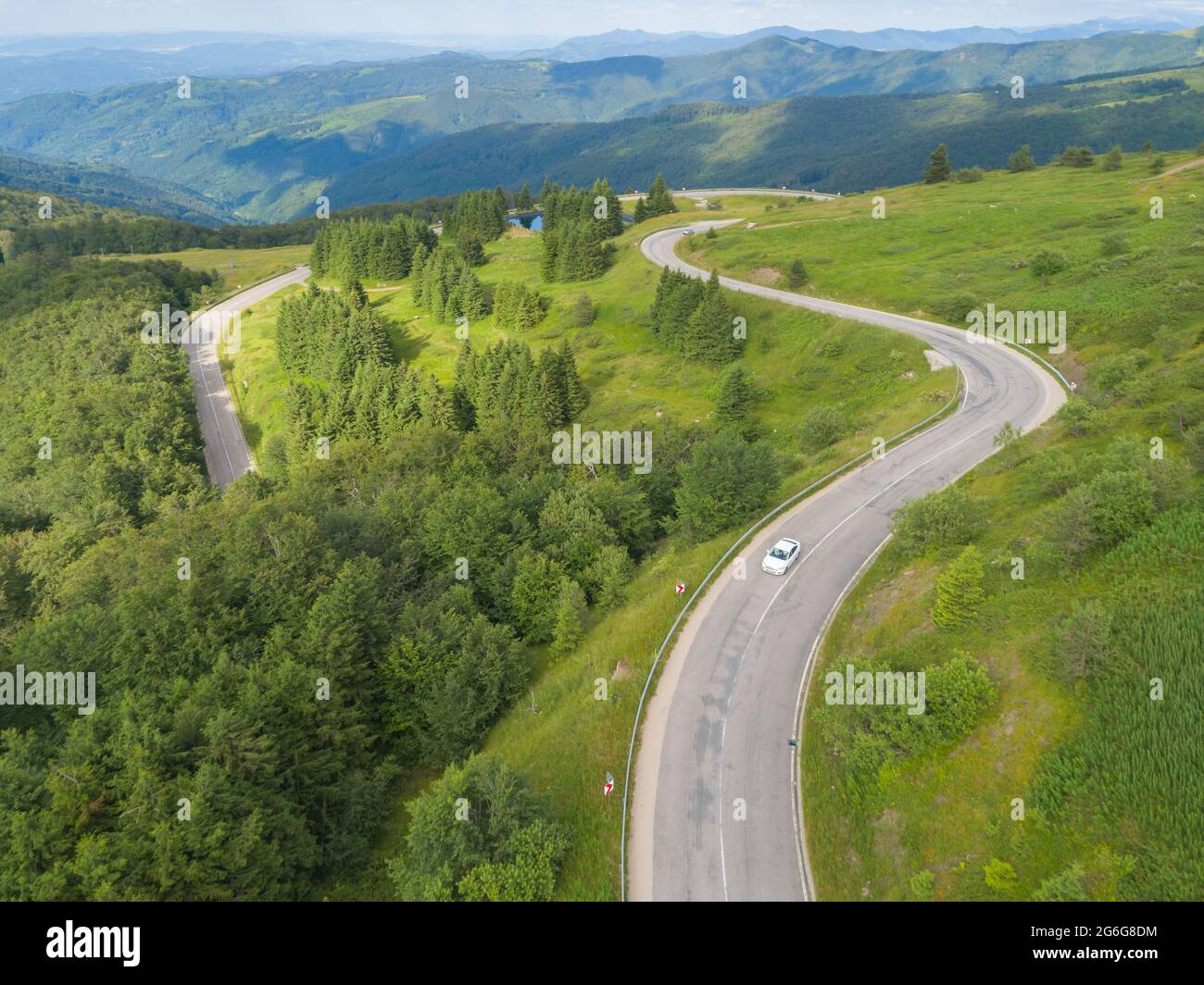 Drone seguire auto bianca su strada di passaggio di montagna con bella foresta Foto Stock