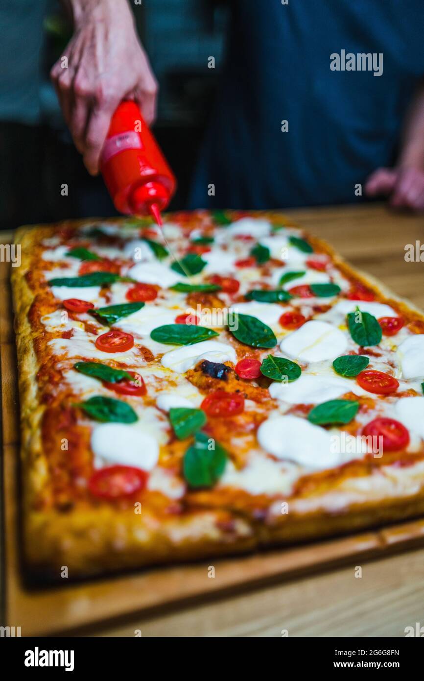 Cucina italiana, pizza con pomodori, mozzarella e basilico fresco verde. Foto Stock