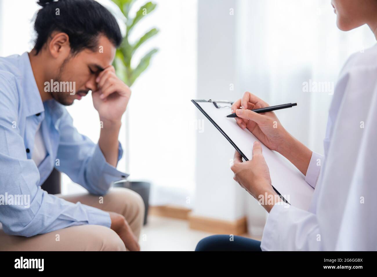 Donna asiatica professionista psicologa medico scrivere, nota su carta e dare la consultazione a pazienti uomo in camera di casa o ospedale sala esame, menta Foto Stock