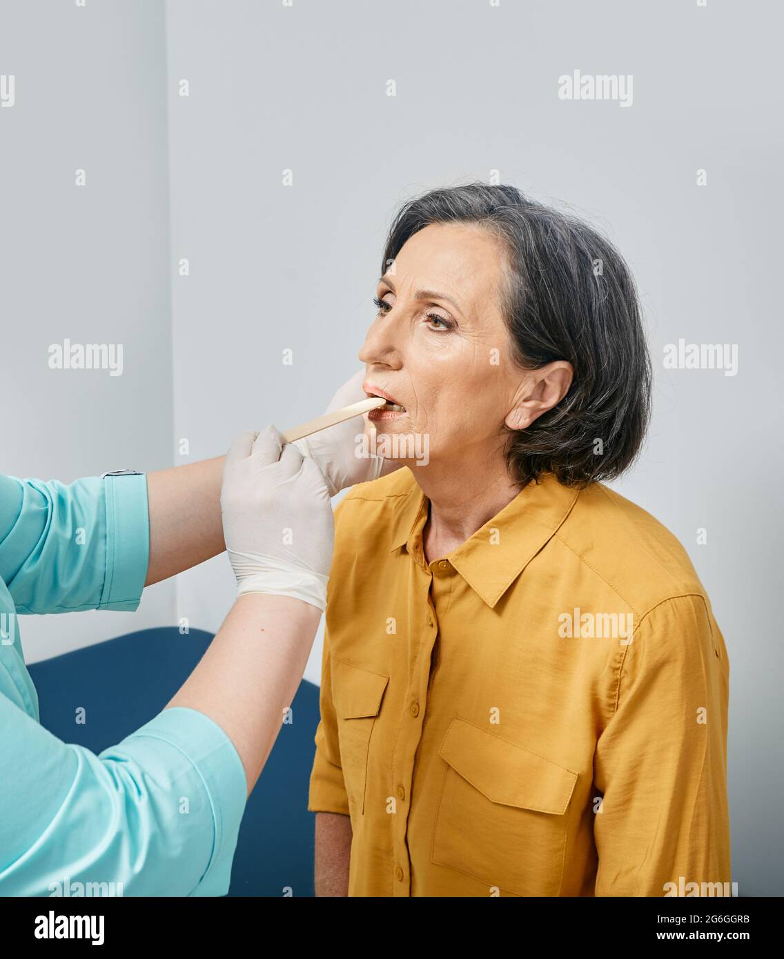 Donna anziana durante l'esame della gola presso la clinica medica. Consultazione medico ENT Foto Stock