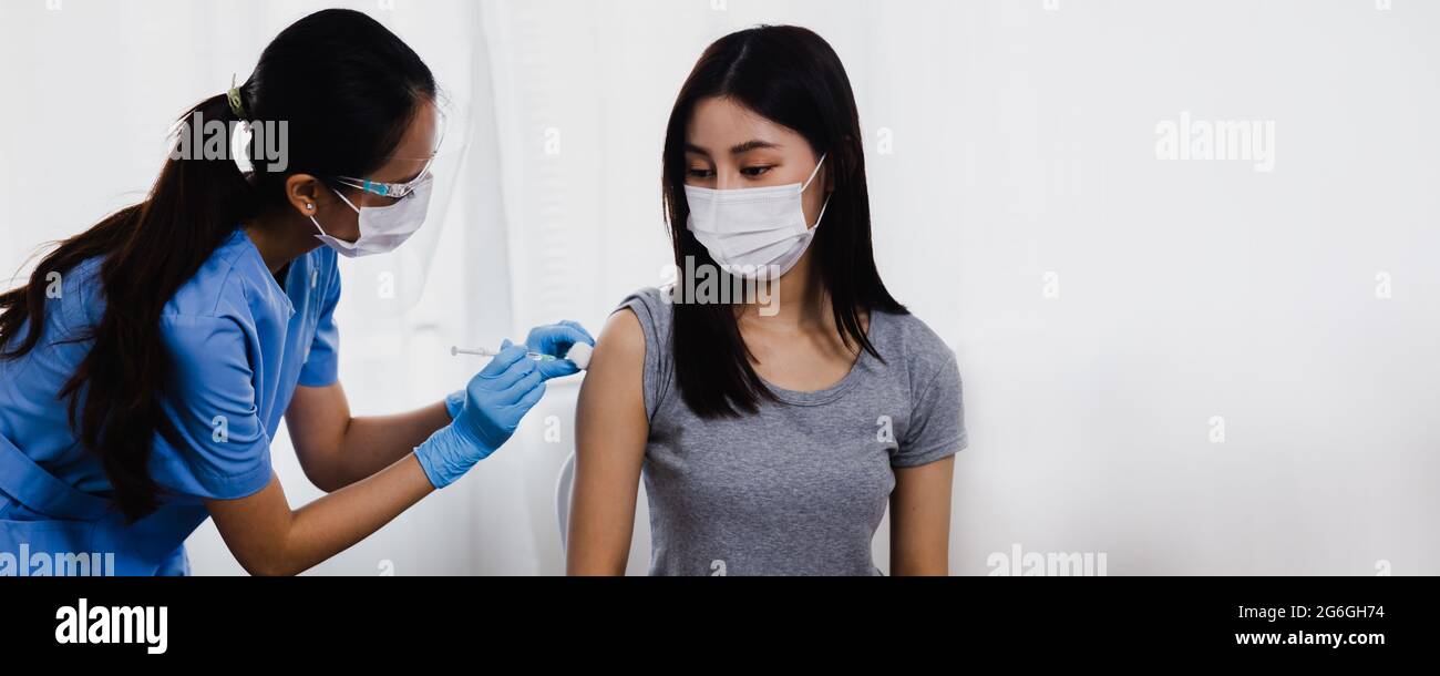 Donna asiatica medico che tiene la siringa e che usa il cotone prima di fare l'iniezione alla gente del paziente in maschera medica. Vaccino Covid-19 o coronavirus Foto Stock