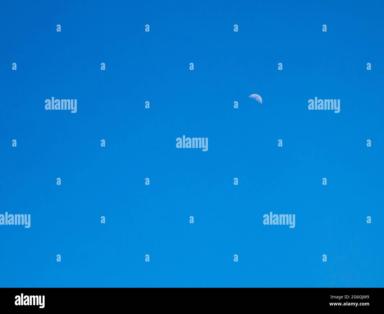Luna visibile, poco dopo mezzogiorno in un cielo blu puro Foto Stock