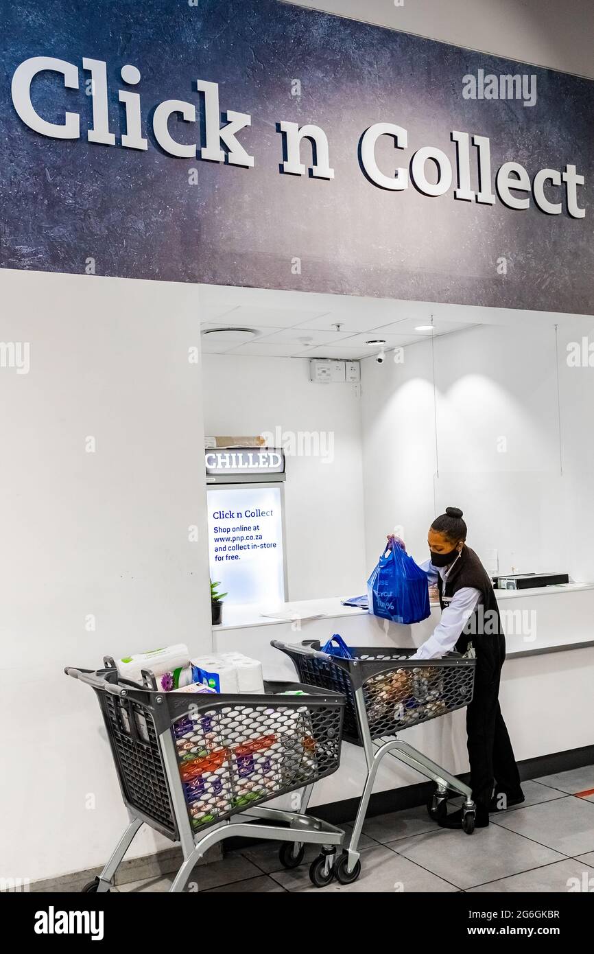 Città del Capo, Sud Africa - 10 dicembre 2020: Membro del Taff che controlla l'ordine in linea della drogheria per il servizio di consegna a domicilio espresso al supermarchio locale di paga del Pick n Foto Stock