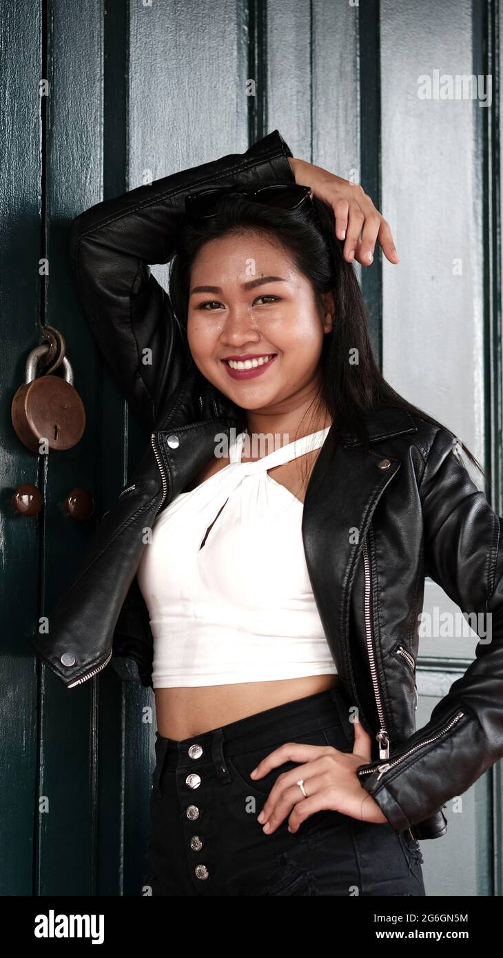 Cinese Asian modello femminile Poser attrice indossando giacca di pelle  nera blusa bianca che si trova nella porta di legno di una casa Heritage  Bangkok Thailandia Foto stock - Alamy