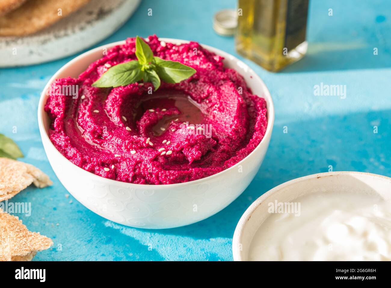 Ciotola humus. Hummus di barbabietola rossa con verdure fresche, olio d'oliva su tavola Foto Stock