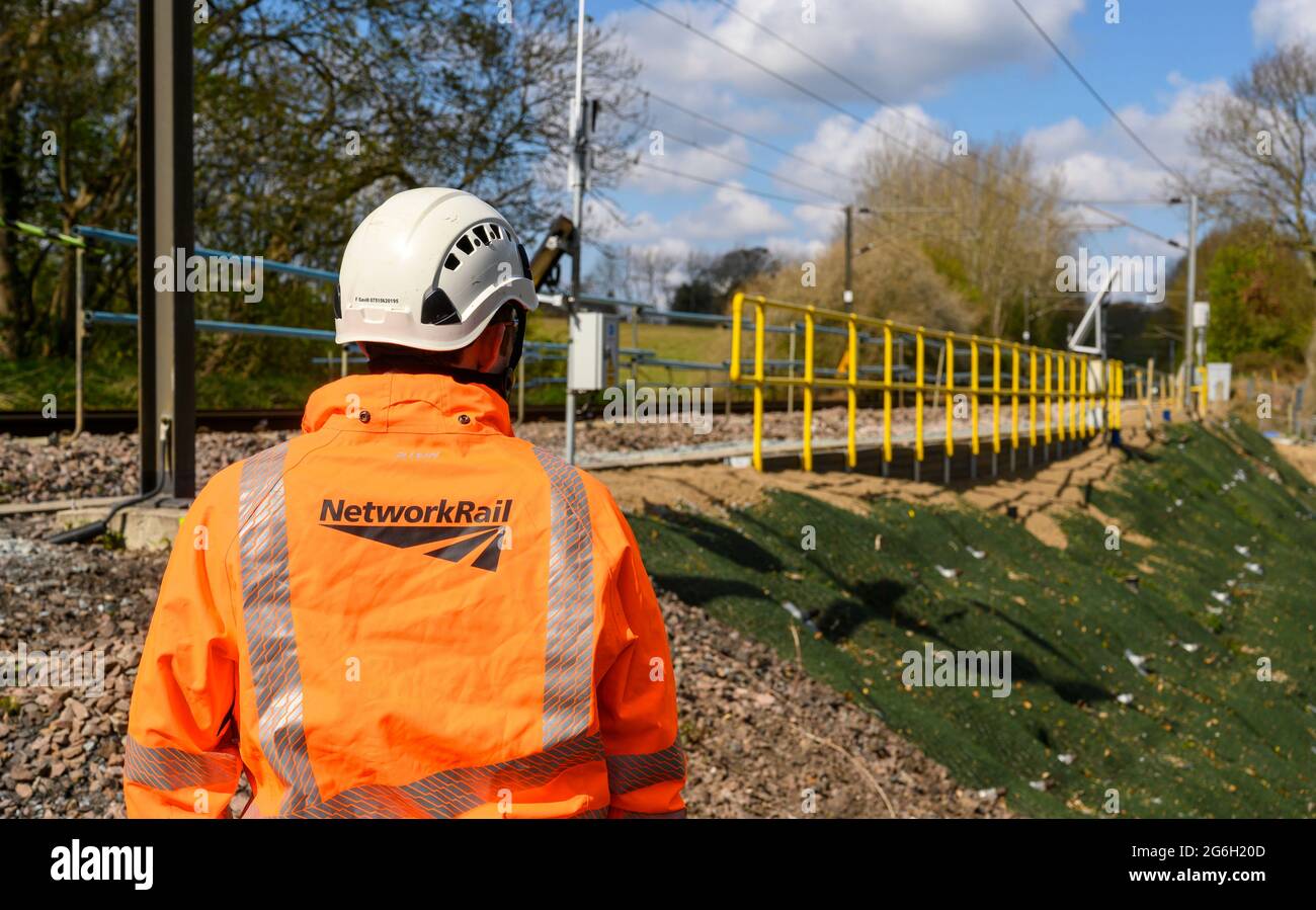 Network Rail worker in piedi al lato della pista ferroviaria a Manningtree, Essex, Inghilterra. Foto Stock