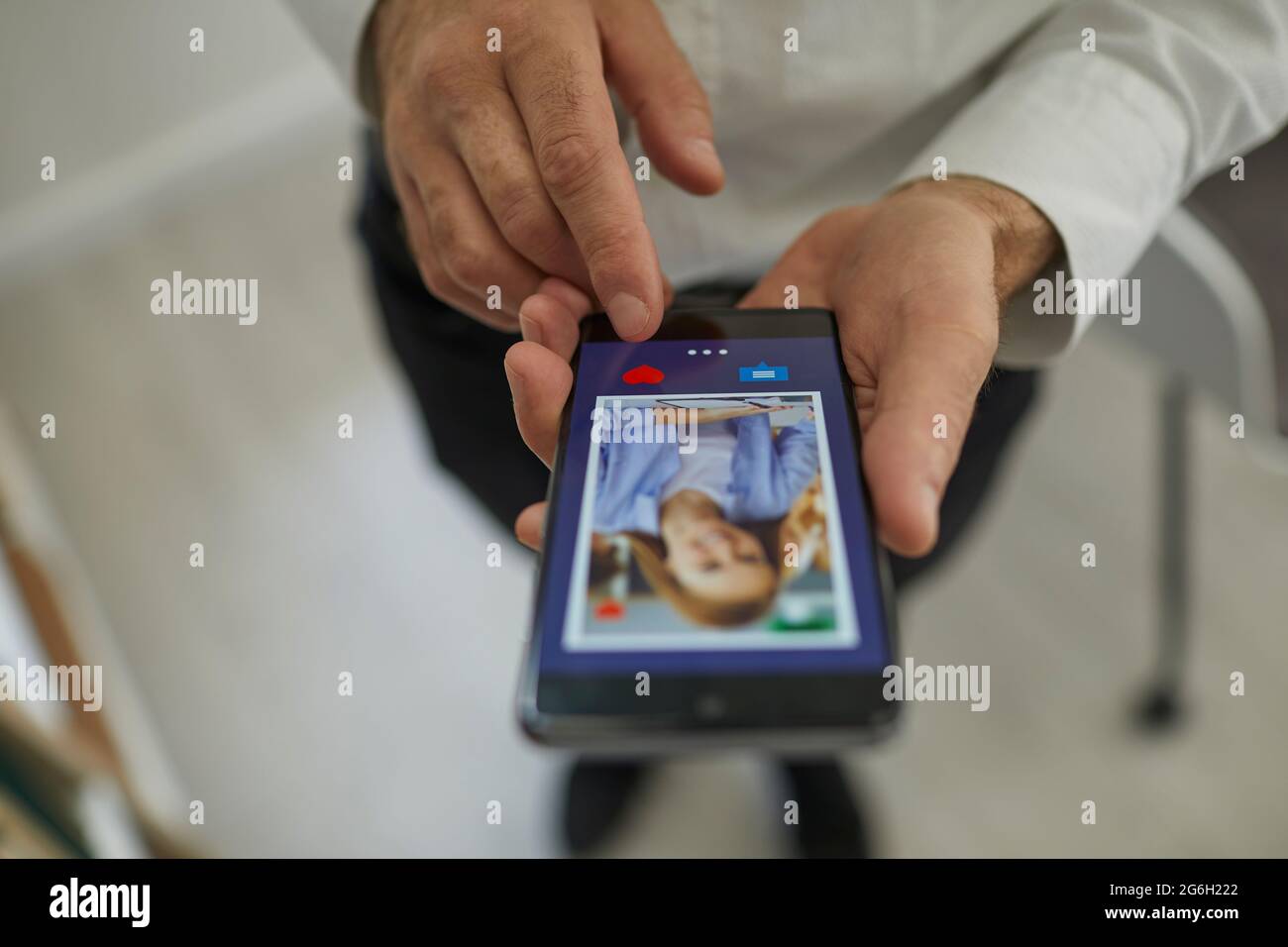 Uomo che usa uno smartphone per scorrere i profili delle donne e premere un pulsante del cuore con il dito. Foto Stock