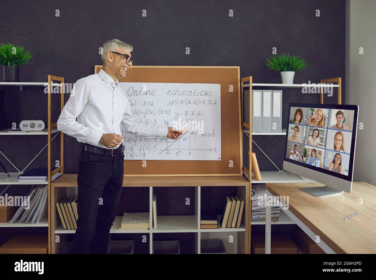 L'insegnante di sesso maschile più anziano conduce una classe sul principio dell'educazione online con i suoi studenti. Foto Stock