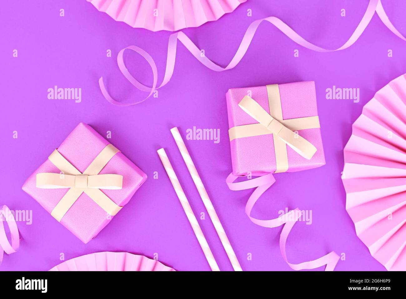 Piatto di festa viola con scatole regalo rosa, streamer di carta, cannucce da bere e rosette di carta Foto Stock