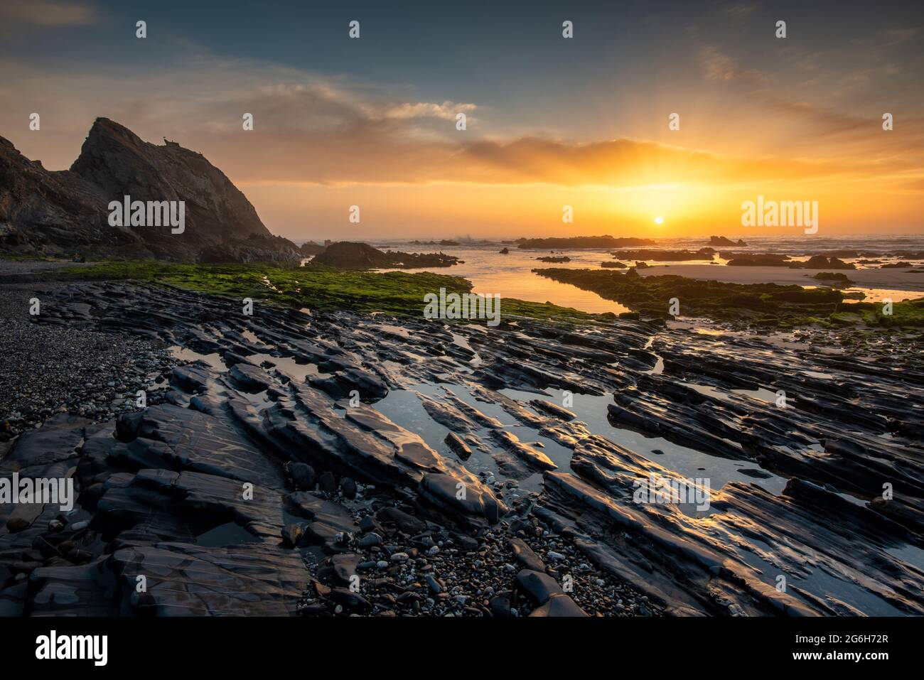 Paesaggio con tramonto sulla costa occidentale portoghese e rocciosa Praia do vale dos Homens Foto Stock