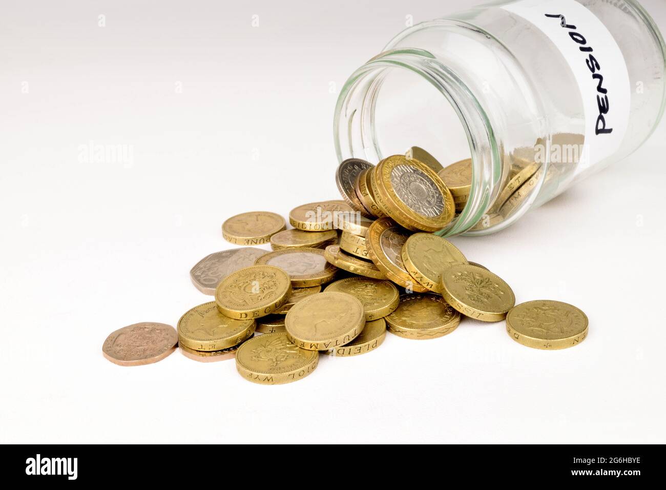 Una fotografia di monete in sterline che fuoriescono da un vaso di vetro. Una metafora della pensione privata. Foto Stock