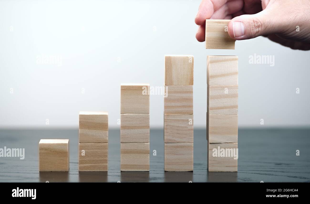 primo piano di mano di persona impilando blocchi di legno, crescita economica e business successo concetto Foto Stock