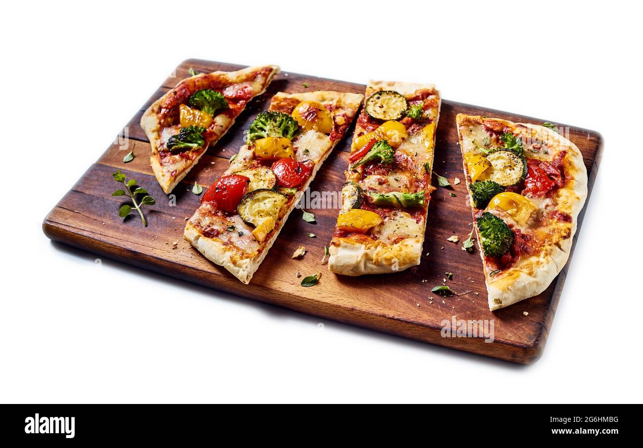 Dall'alto della gustosa pizza vegetariana con verdure assortite poste su tritare in legno su sfondo bianco isolato Foto Stock