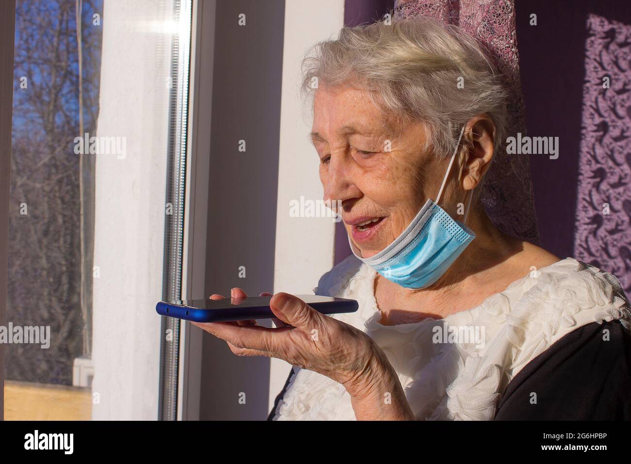 Nonna con smartphone che fa un messaggio audio sul gadget, donna matura che usa il cellulare con assistente vocale digitale virtuale. Covid-19, salute, pandemia - senior a casa per la protezione dal virus Foto Stock