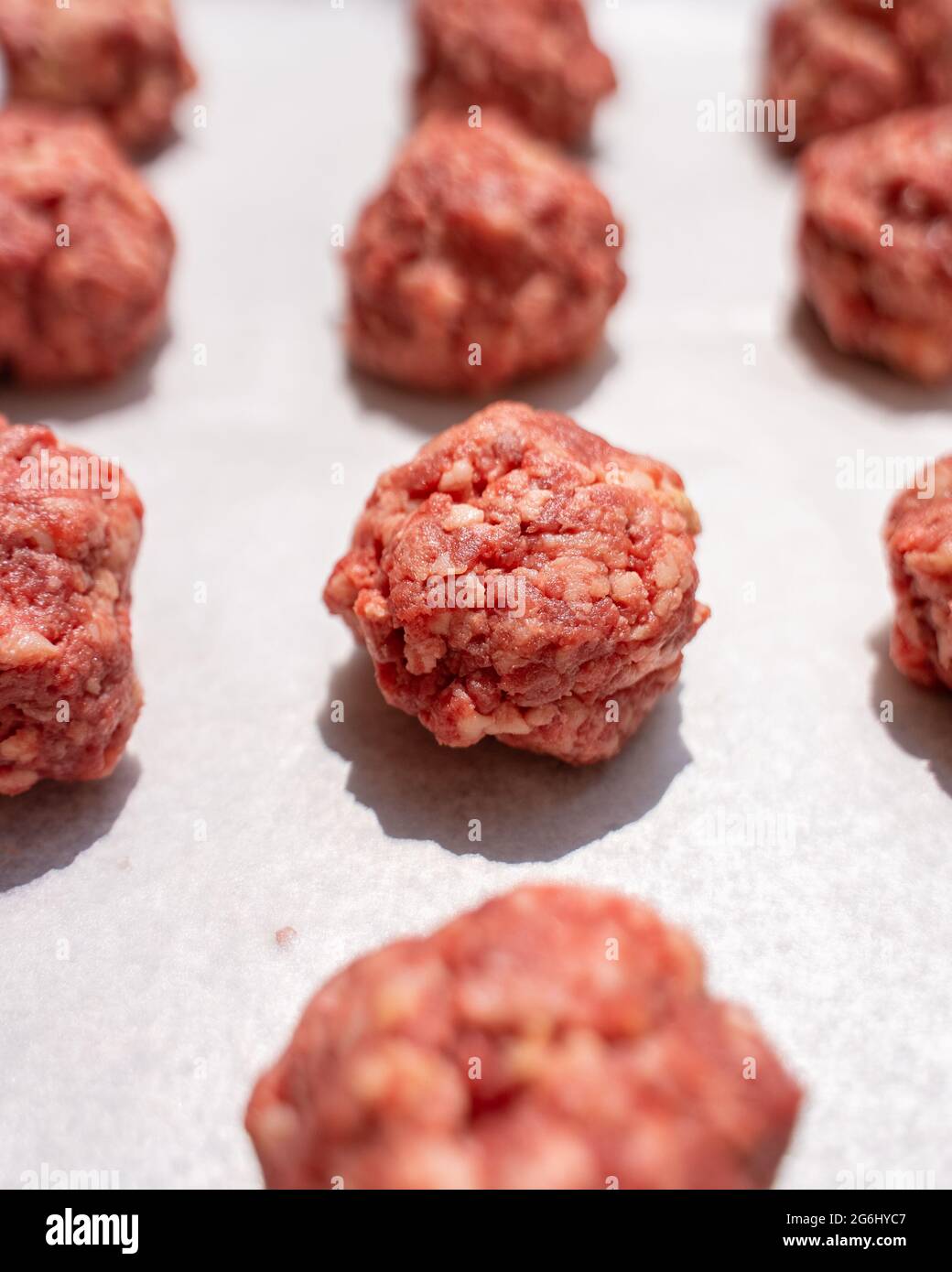 File di polpette crude preparate con carne macinata su carta di cera Foto Stock