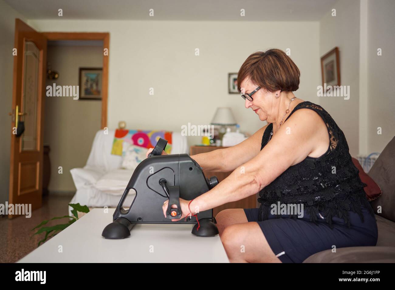 Una donna anziana fa esercizi a pedale con le mani Foto Stock