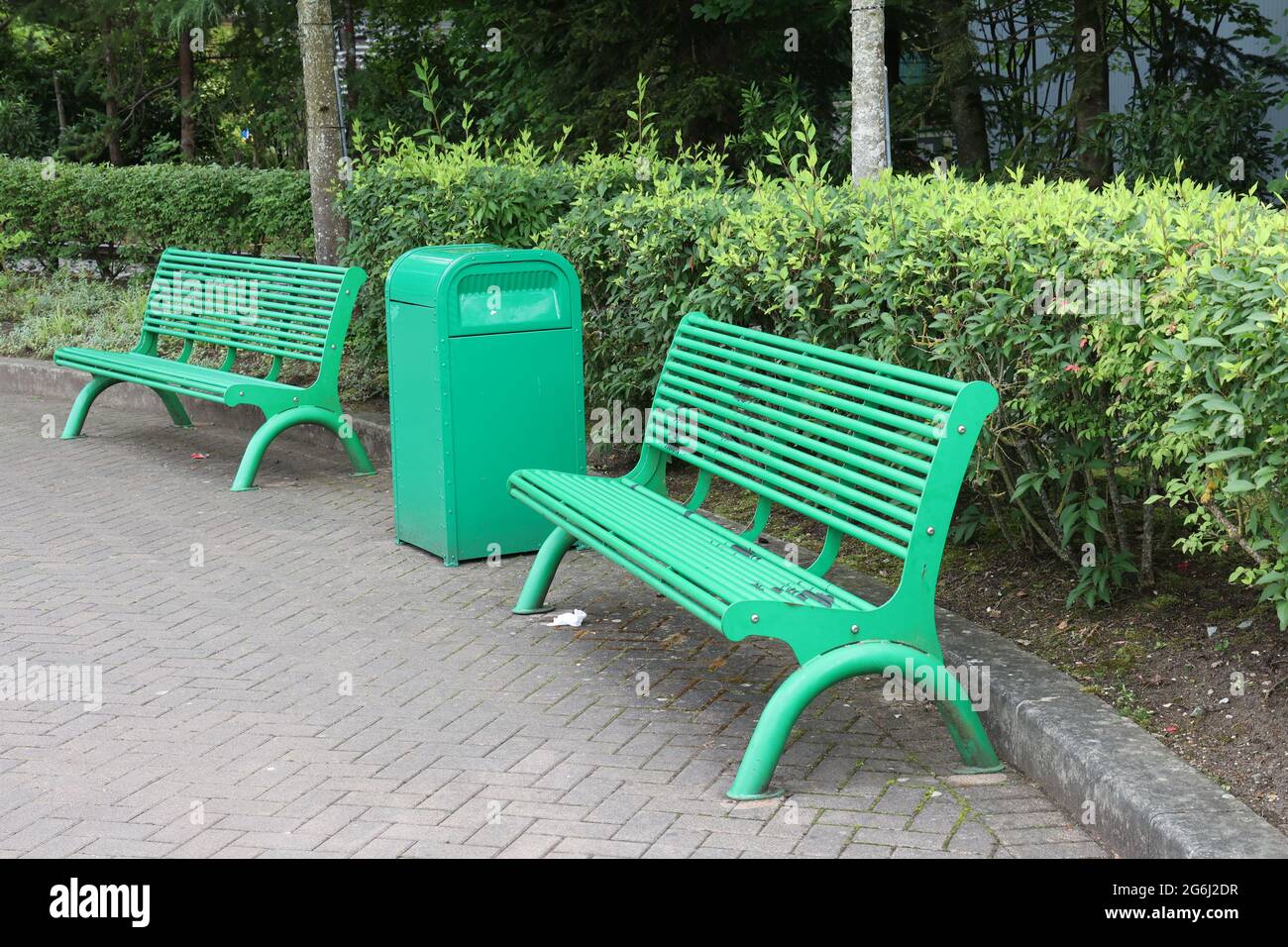 Panchine in metallo verde nel parco per la ricreazione dei visitatori Foto Stock