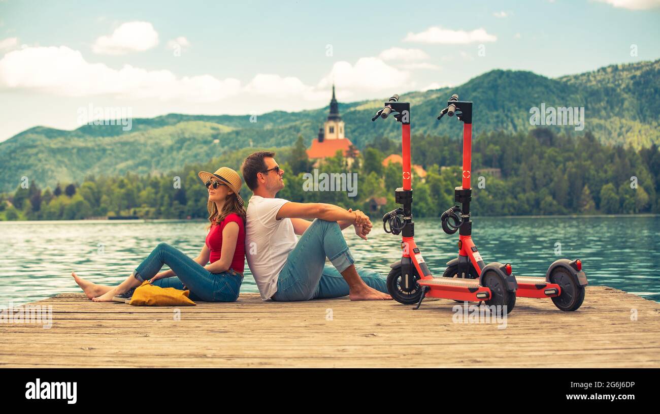 Giovane coppia che usa lo scooter elettrico come moderno mezzo di trasporto ecologico mentre esplora il verde paese Slovenia in vacanza. Energia ecologica verde Foto Stock