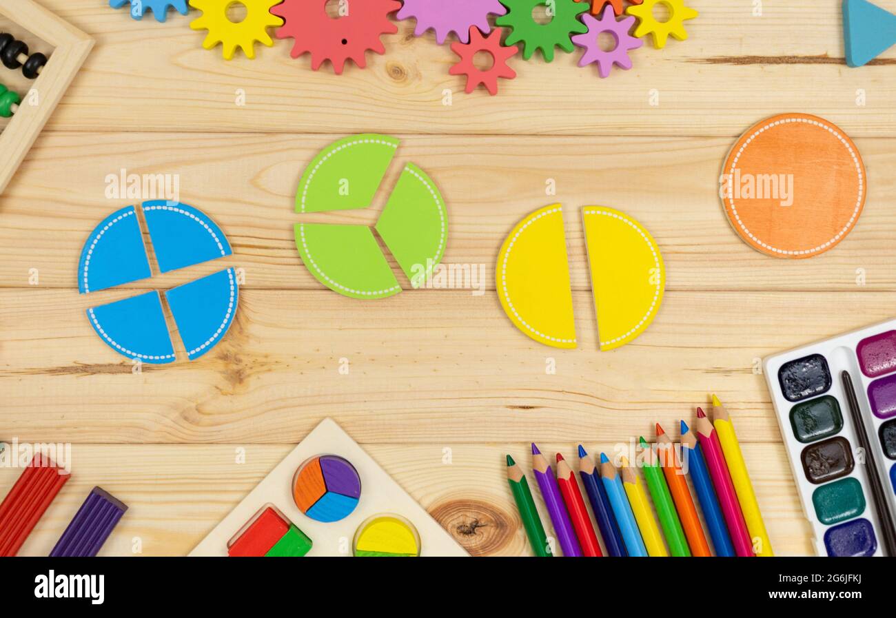 Frazioni matematiche colorate, cubi, matite su tavola di legno. Matematica interessante per i bambini. Educazione, concetto di ritorno alla scuola Foto Stock