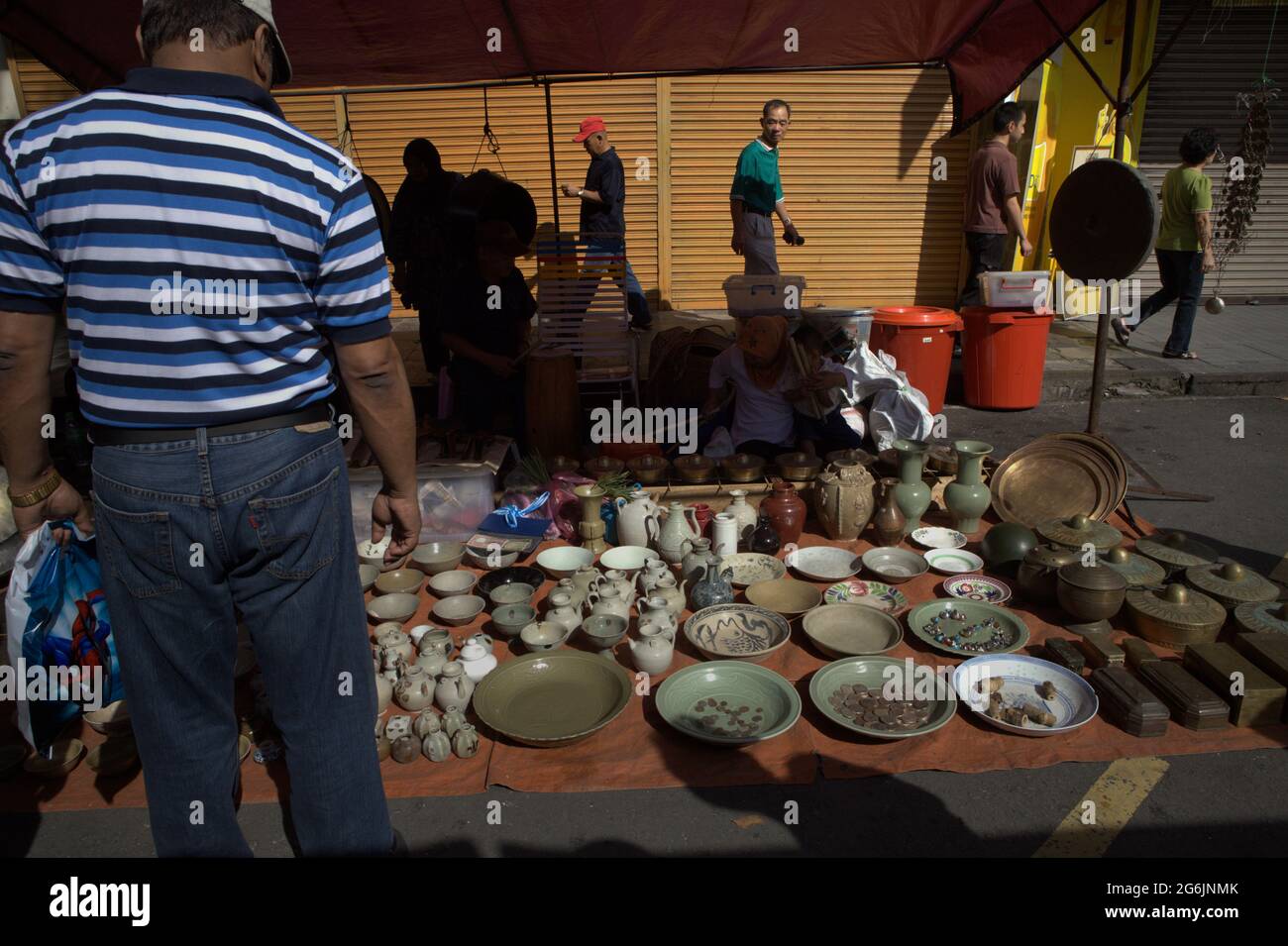 Un uomo che presta attenzione al gres di porcellana ad un venditore durante il mercato domenicale di Gaya su Gaya Street, Kota Kinabalu, Sabah, Malesia. Foto Stock