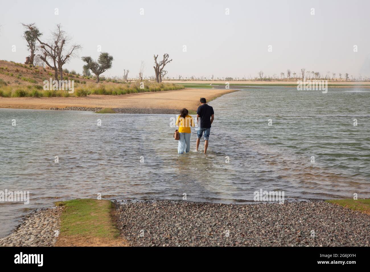 Una coppia attraversa l'acqua presso i Love Lakes di al Qudra, Dubai, Emirati Arabi Uniti. --- i laghi d'amore di Dubai sono costituiti da due laghi artificiali a forma di cuore. Il l Foto Stock