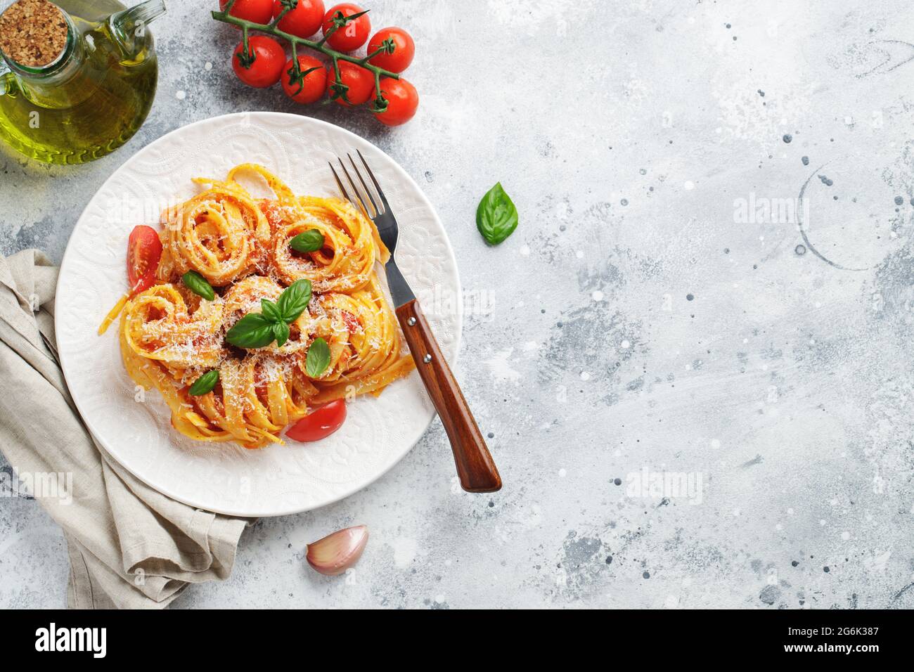 Gustosa e appetitosa classica tagliatelle italiana con salsa di pomodoro, parmigiano e basilico su piatto su tavolo leggero. Vista dall'alto, orizzontale. Foto Stock