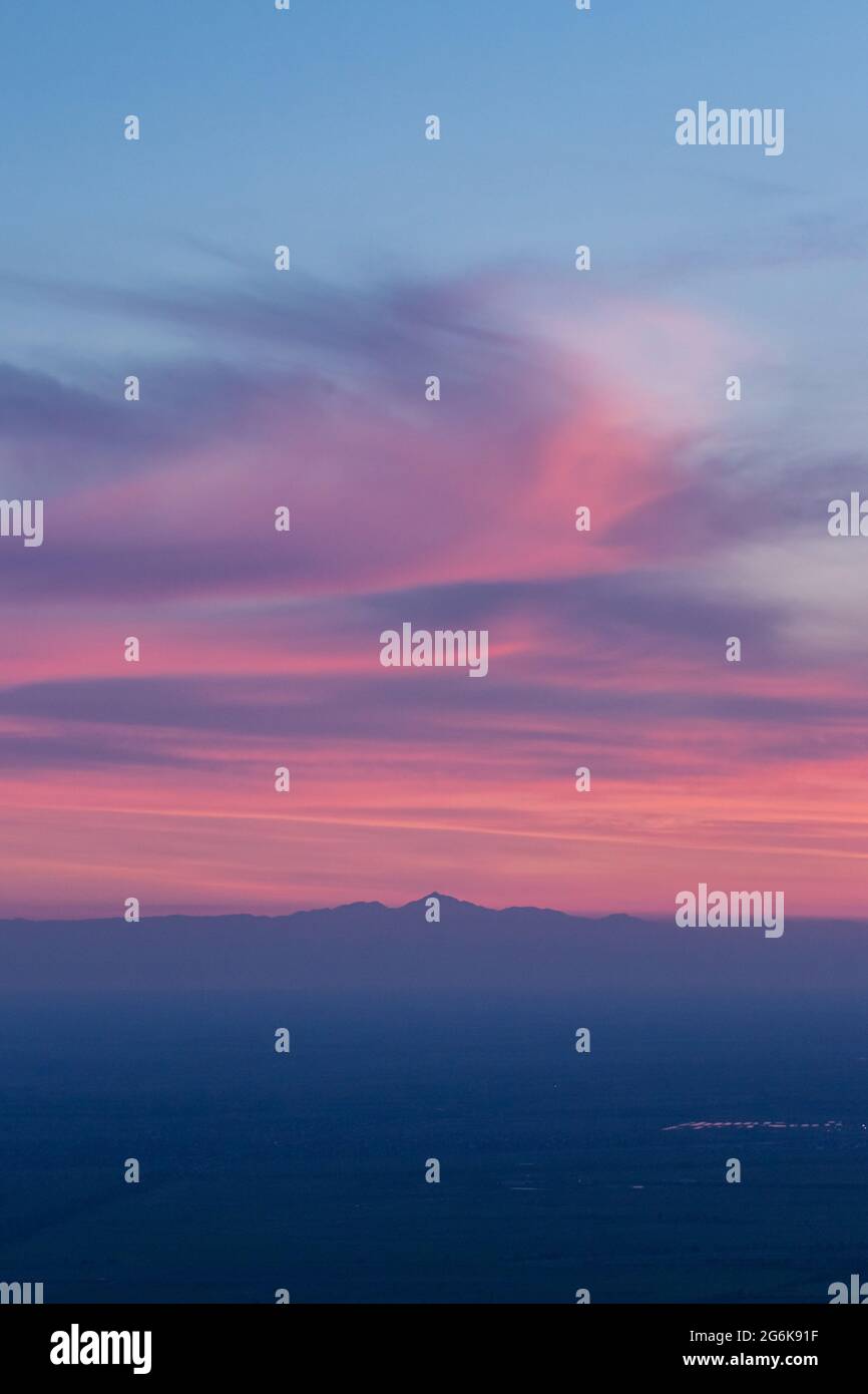 Nuvole rosa e viola prima dell'alba sulle sagome delle vette di montagna Foto Stock